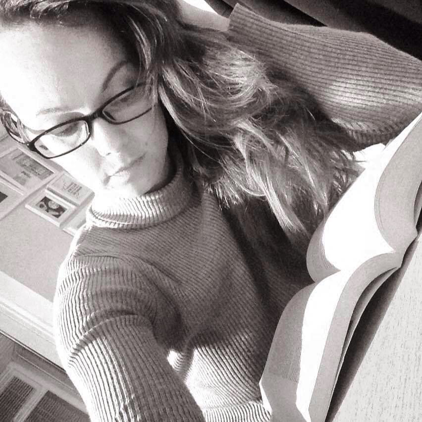 Women in black and white reading a book resting her head in her hand